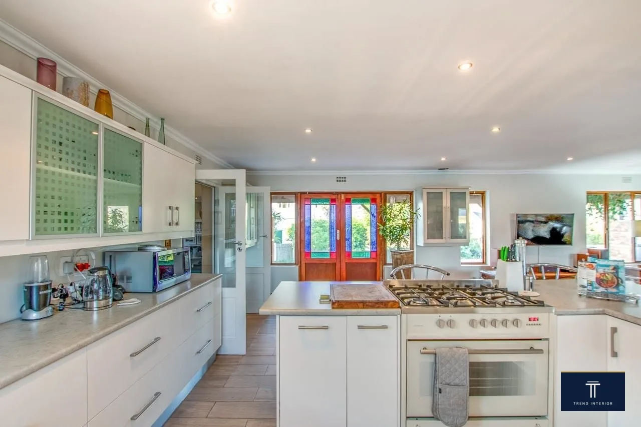 Stainless-steel gas range with five-burner hob and oven, installed in a fully-renovated kitchen with custom cabinetry.