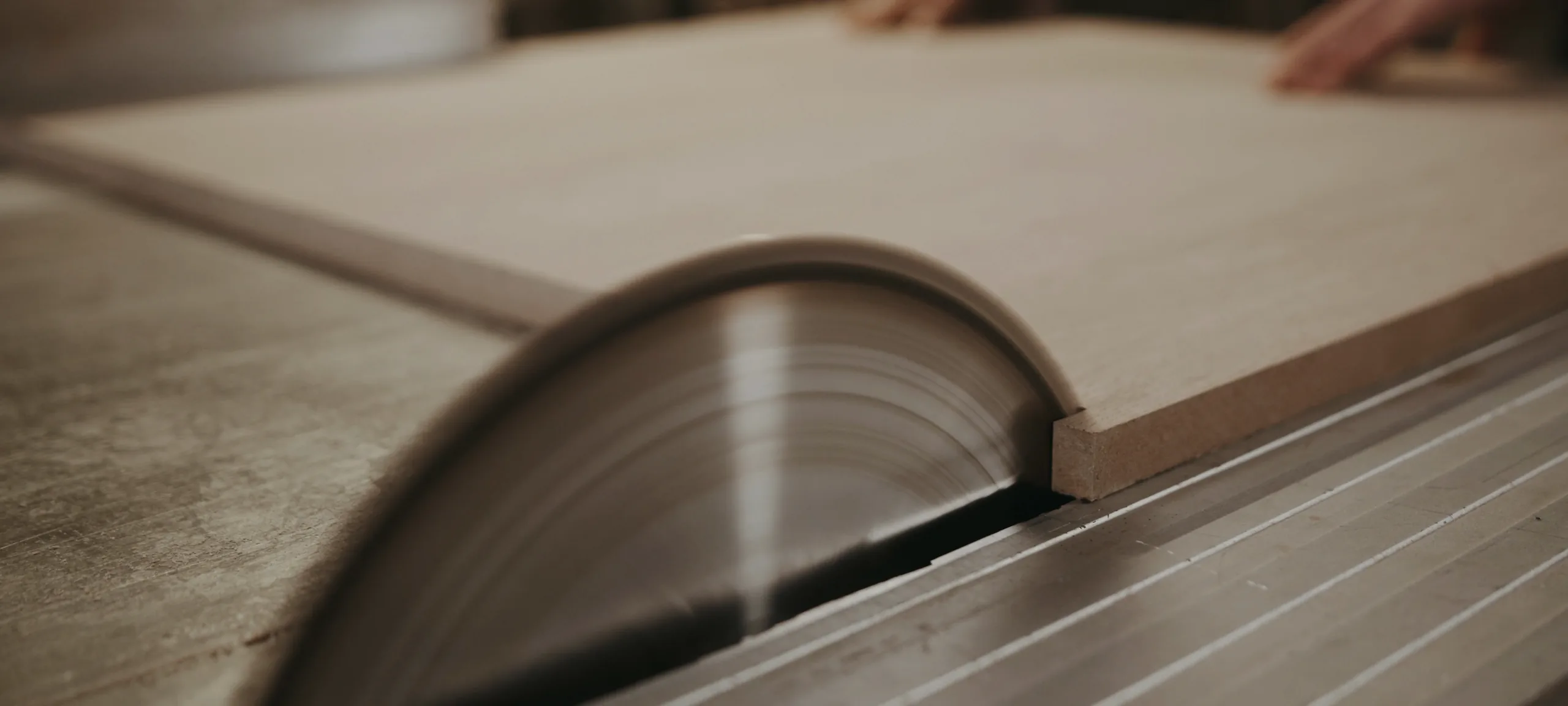 A pale timber board on a Cape Town workshop bench, the saw blade engaged steadily in the kerf line.